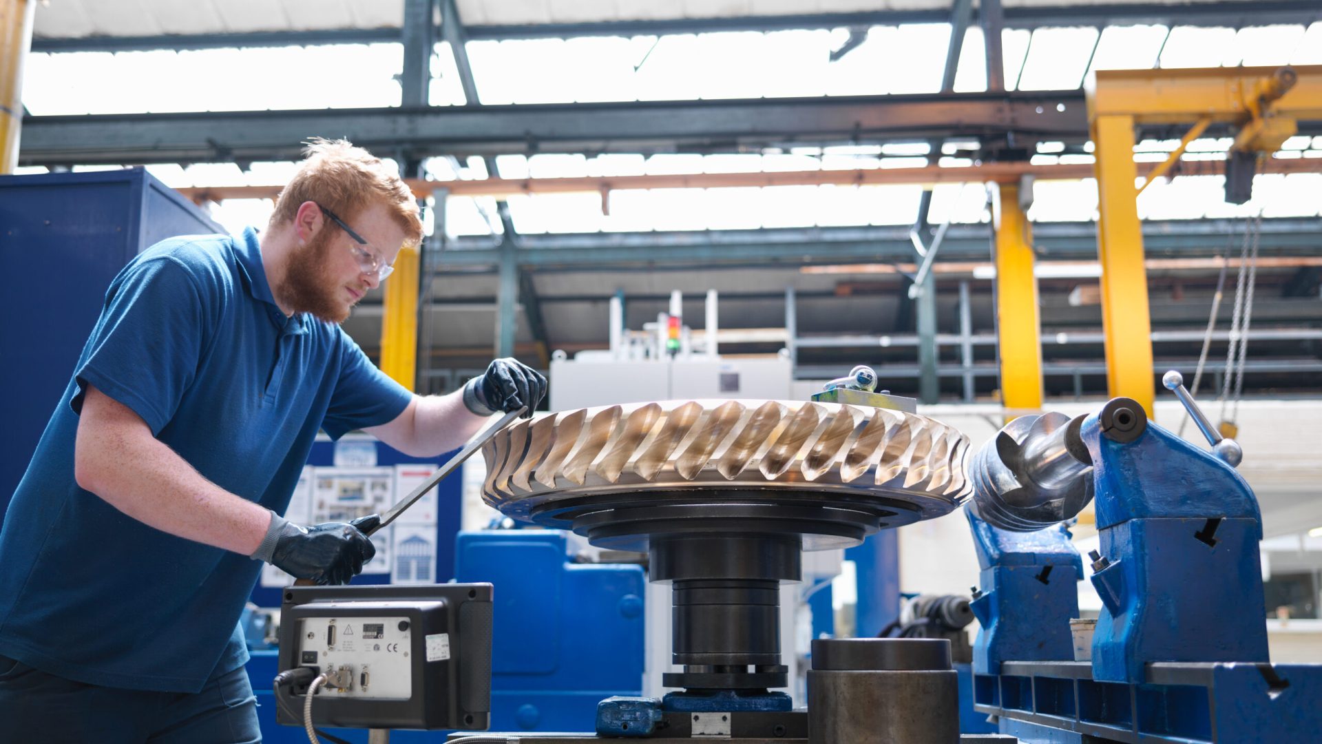 Engineer finishing bronze gear wheel in engineering factory
